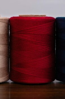 Three yarns that come in tan, red, and navy blue.